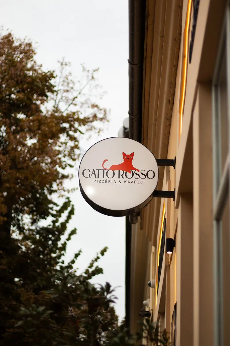 Gatto Rosso pizzéria kerek cégtáblája a homlokzaton